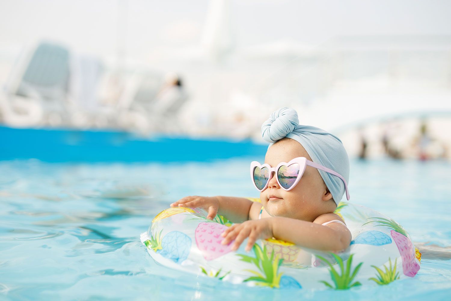 Ein Baby mit Sonnenbrille und Schwimmreifen in einem Pool