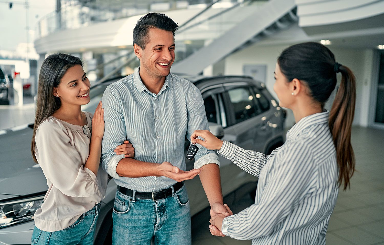 Ein Mann und eine Frau bekommen die Schlüssel für ein Mietwagen überreicht